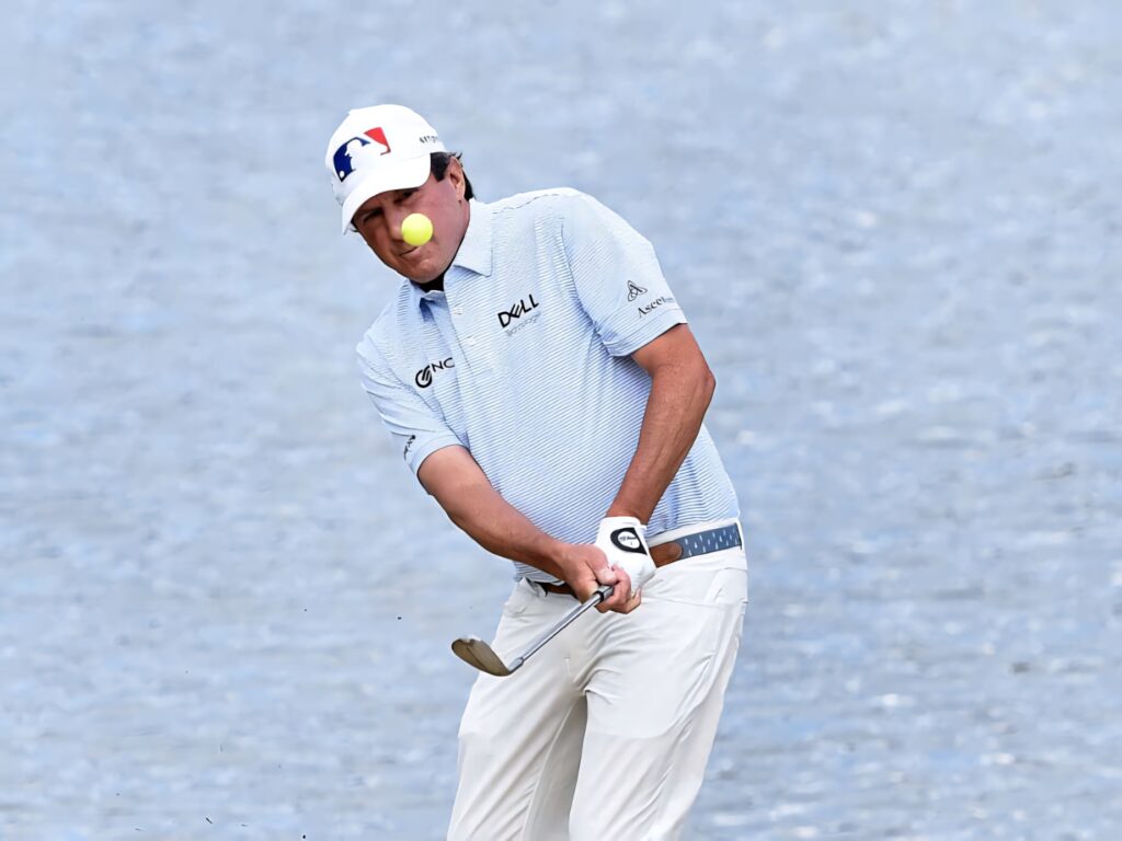 Billy Andrade swinging golf club with ball mid-air against clear blue sky golf wallpaper background