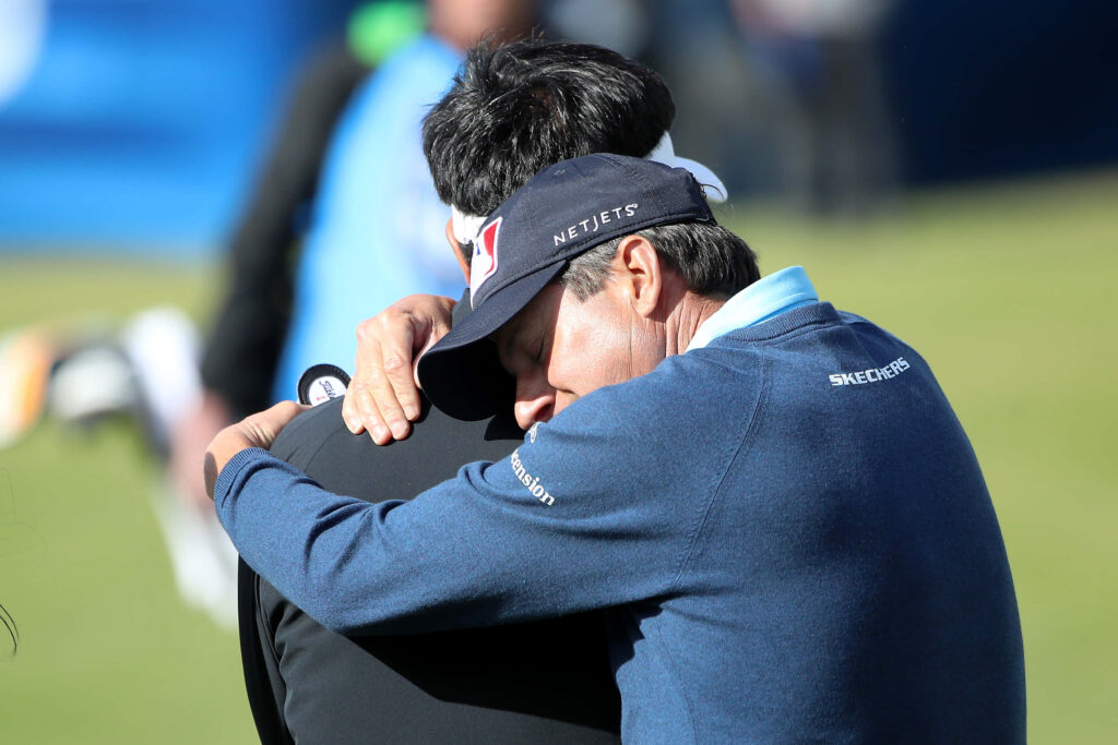 Billy Andrade hugging Y E Yang on golf course showing sportsmanship and camaraderie wallpaper