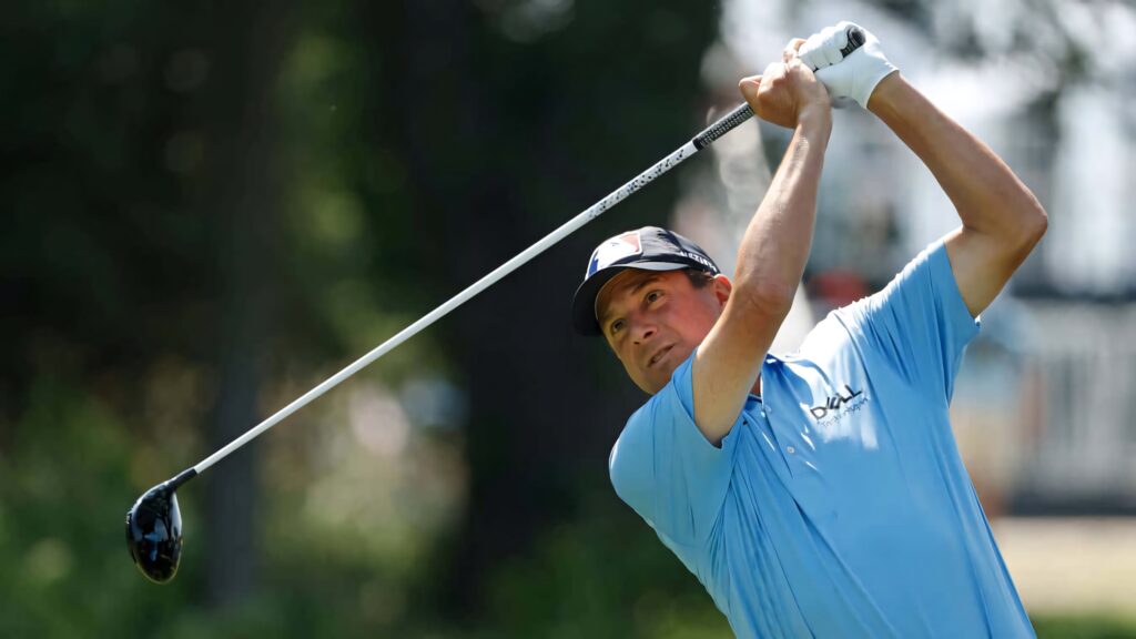Billy Andrade mid-swing on golf course wearing light blue polo shirt focused golf wallpaper background