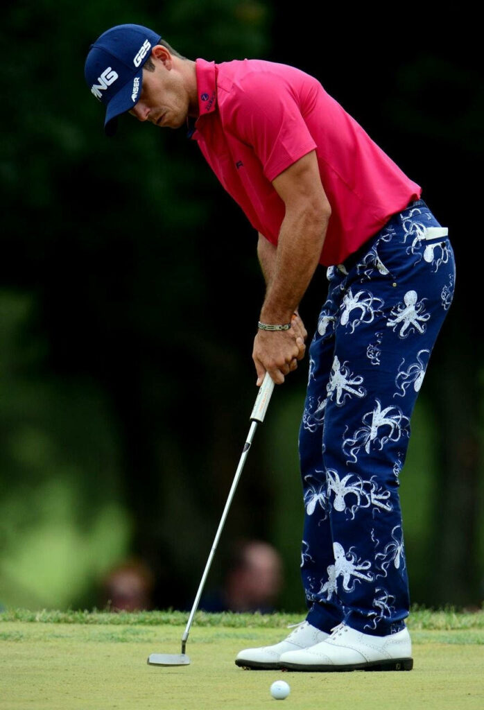 Billy Horschel focused golf stance putting bright pink shirt octopus pattern pants on green grass Wallpaper