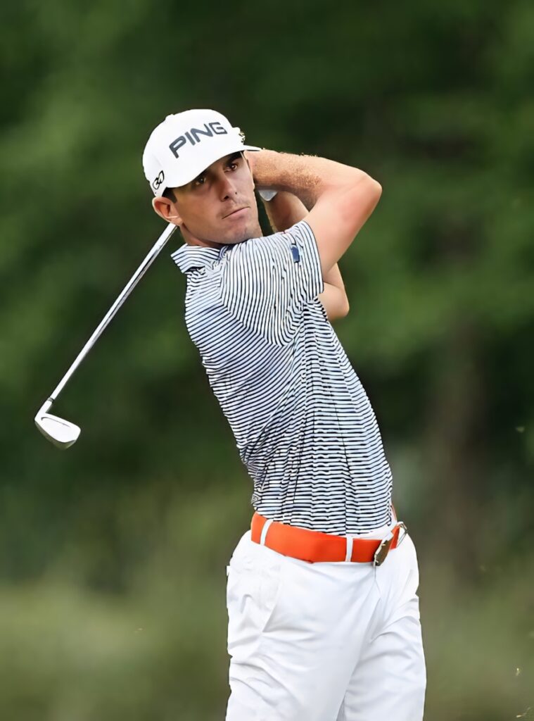 Billy Horschel focused golf swing stance striped shirt orange belt lush green golf course background Wallpaper