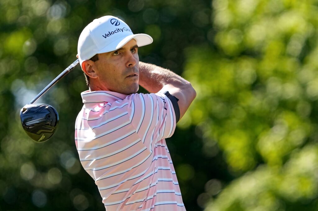 Billy Horschel focused side profile swinging golf club on bright green course wallpaper background