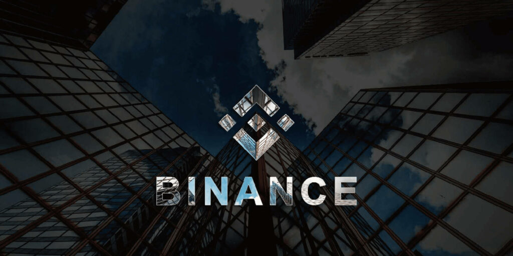 Binance logo on modern wallpaper with glass skyscrapers and dramatic cloudy sky background