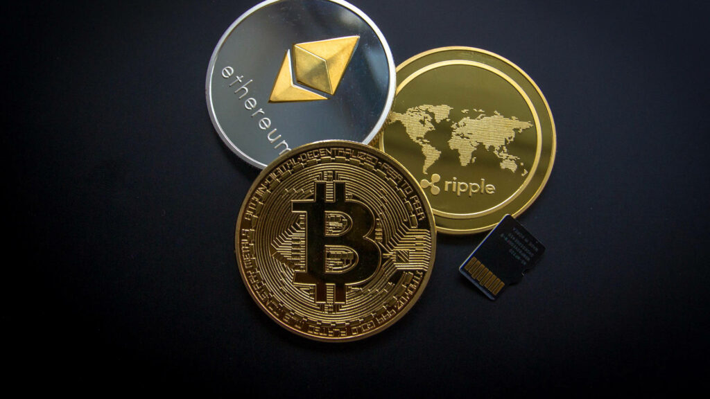 Cryptocurrency wallpaper with gold Bitcoin, silver Ethereum, gold Ripple coin and microSD card background