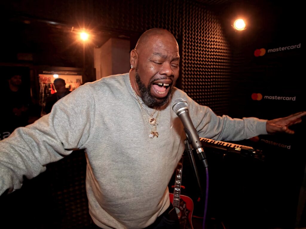Biz Markie performing passionately at microphone in intimate studio with soulful expression wallpaper