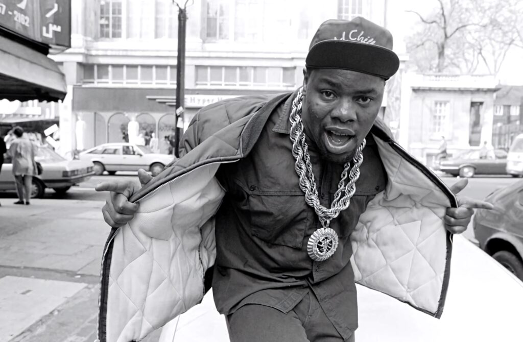 Biz Markie performing hip hop on city street wearing bold chains cap urban street style wallpaper