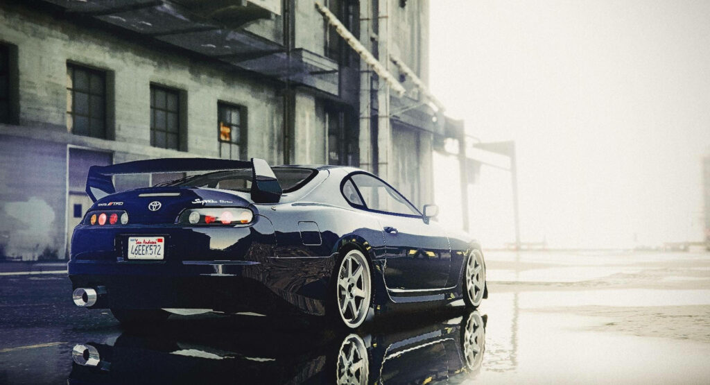 Black 1996 Toyota Supra Mk4 rear view on wet urban street with tail lights and spoiler visible Wallpaper