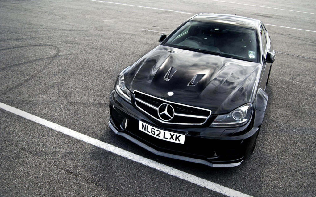 Black 2012 Mercedes-Benz C63 AMG parked on asphalt showcasing aggressive front and sleek lines Wallpaper