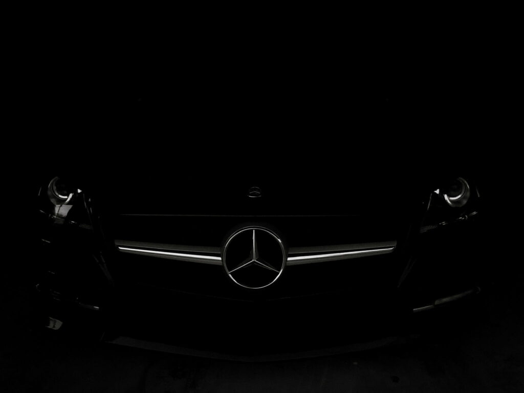Mercedes-Benz SLK AMG in dramatic low lighting showcasing chrome emblem and sharp grille design Wallpaper