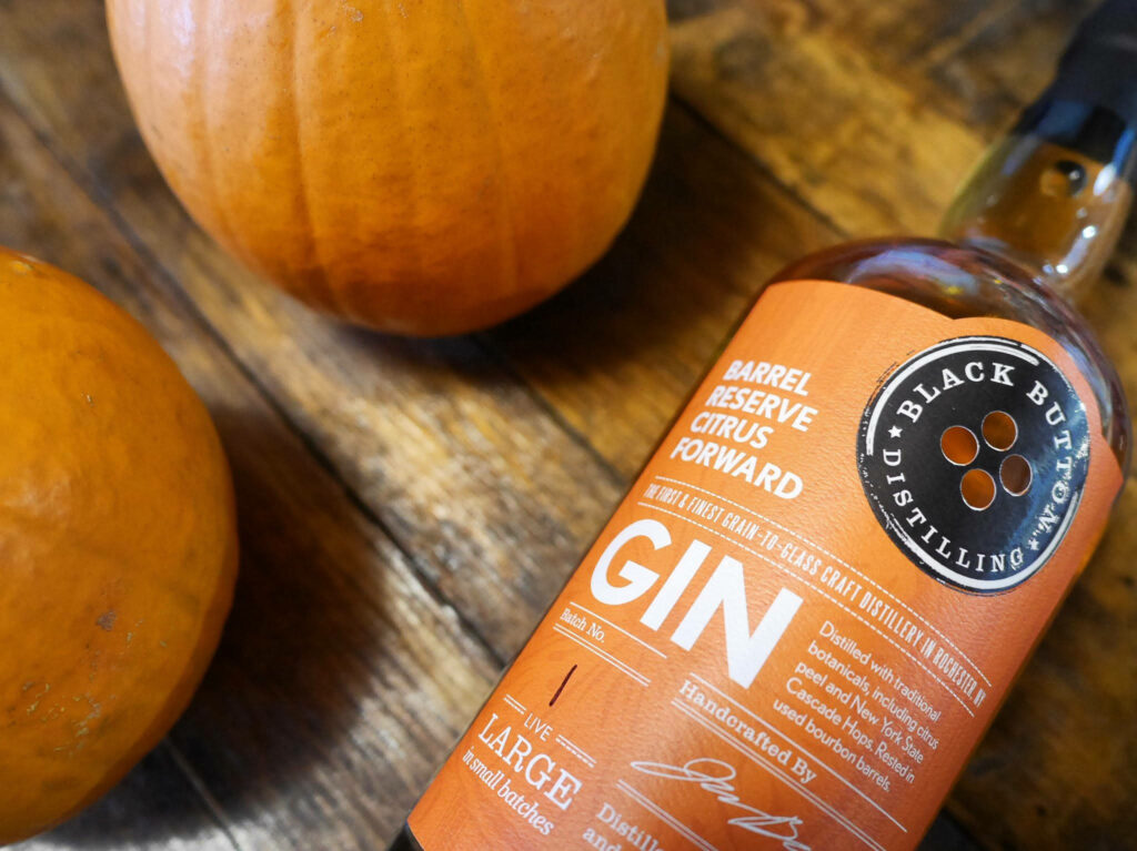 Black Button Distilling Barrel Reserve Citrus Forward Gin bottle on rustic wood with pumpkins autumn Wallpaper