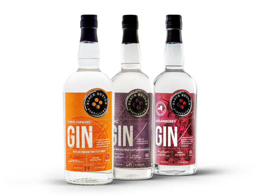 Three bottles of Black Button Distilling gin with bright orange label citrus forward flavor wallpaper