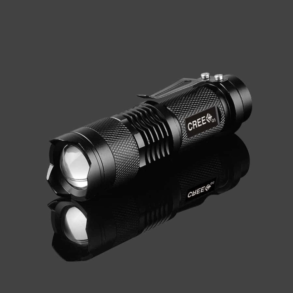 Black CREE Q5 tactical flashlight with textured metal body on dark reflective surface studio shot Wallpaper