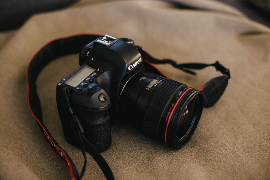Black Canon DSLR with 35mm f1.4L lens on khaki fabric minimalist photography wallpaper background