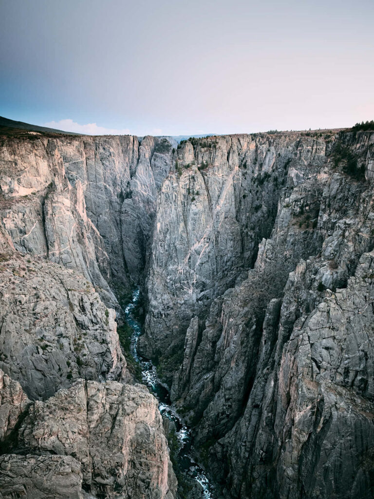 Breathtaking Black Canyon cliffs with rugged terrain and a narrow river winding through gorge Wallpaper