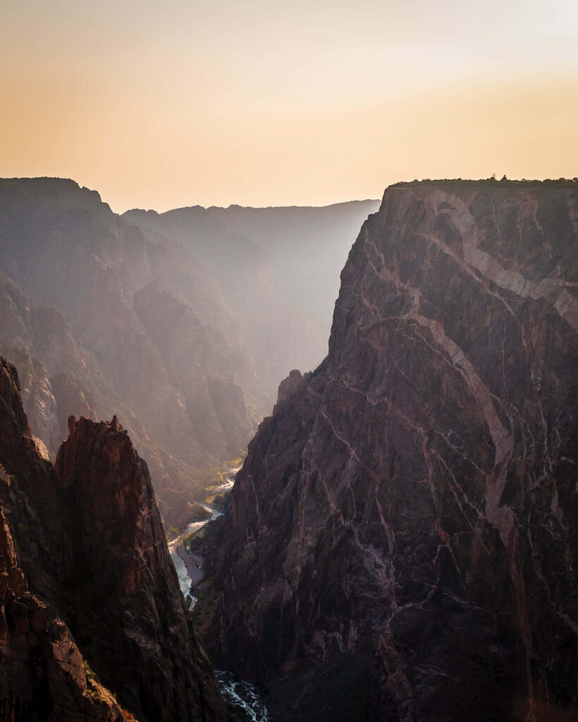 Black Canyon Colorado sheer cliffs rugged rock formations golden light winding river deep canyon view Wallpaper