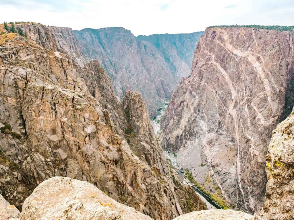 Towering rugged cliffs with narrow winding river in Black Canyon adventurous landscape wallpaper