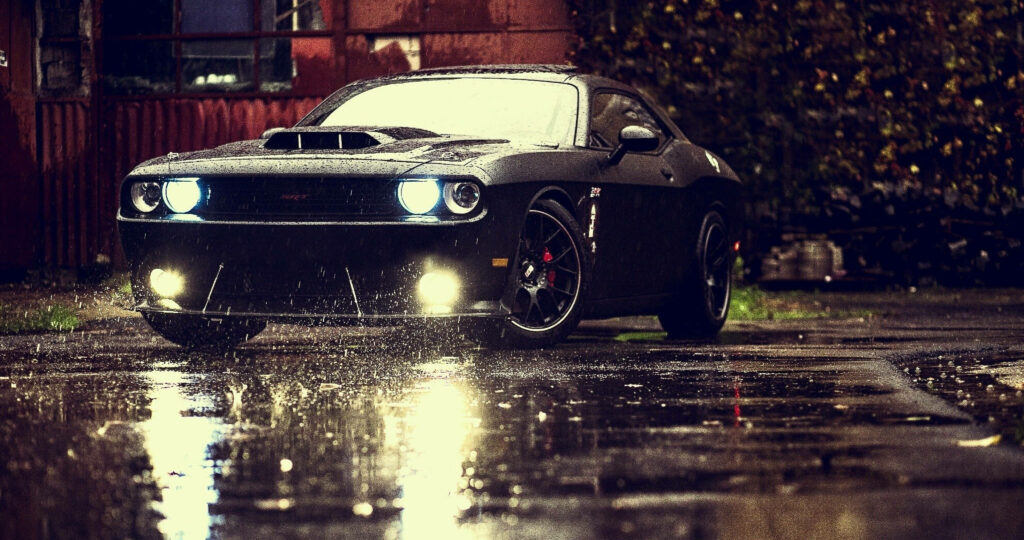 Black Dodge Challenger Demon parked on wet road at night with bright headlights reflection Wallpaper