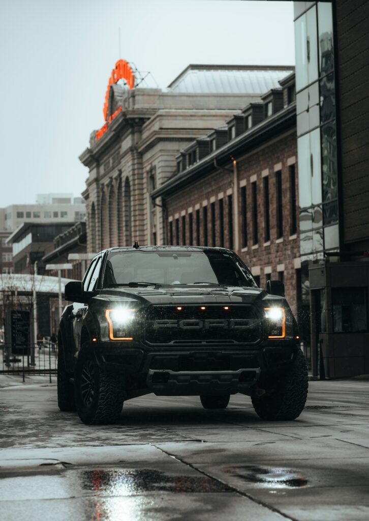 Black Ford Raptor SUV on Wet City Road - Urban Night Scene Wallpaper