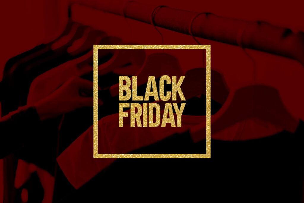 Black Friday bold golden glitter text with shimmering gold frame on dark red background shopping racks Wallpaper
