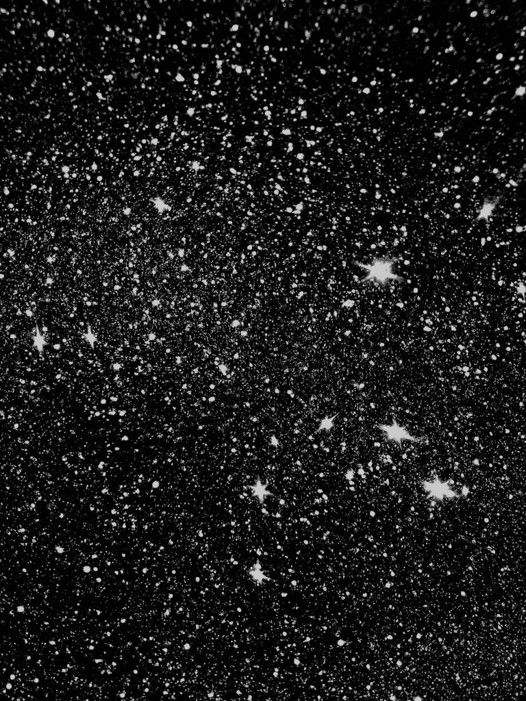 Black glitter wallpaper with textured white chunks on deep shimmering background starry night design