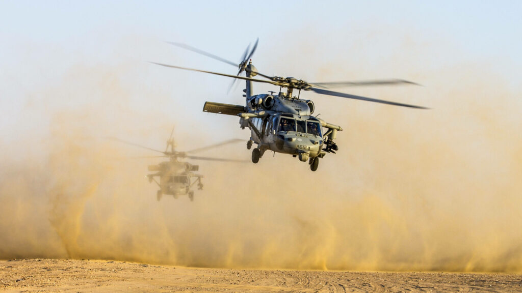 Black Hawk Helicopter taking off over dusty dry desert landscape with swirling dust cloud Wallpaper