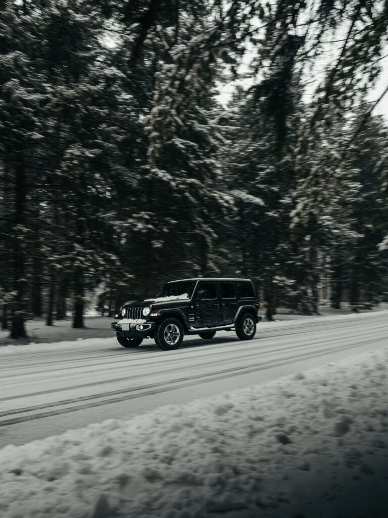 Black Jeep Wrangler on Snowy Road: Rugged Winter Wallpaper