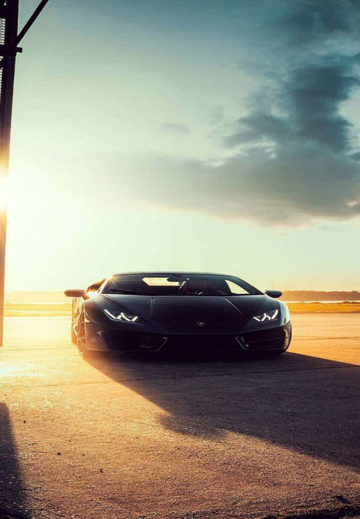 Black Lamborghini on desert runway at sunset with golden light perfect iPhone wallpaper background