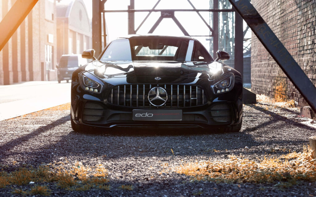 Front view of black Mercedes car with bold grille and emblem parked outdoors in sunlight Wallpaper