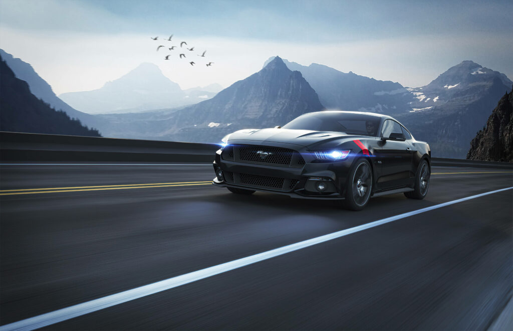 Black Mustang speeding on empty mountain highway under dramatic sky with distant peaks and birds Wallpaper