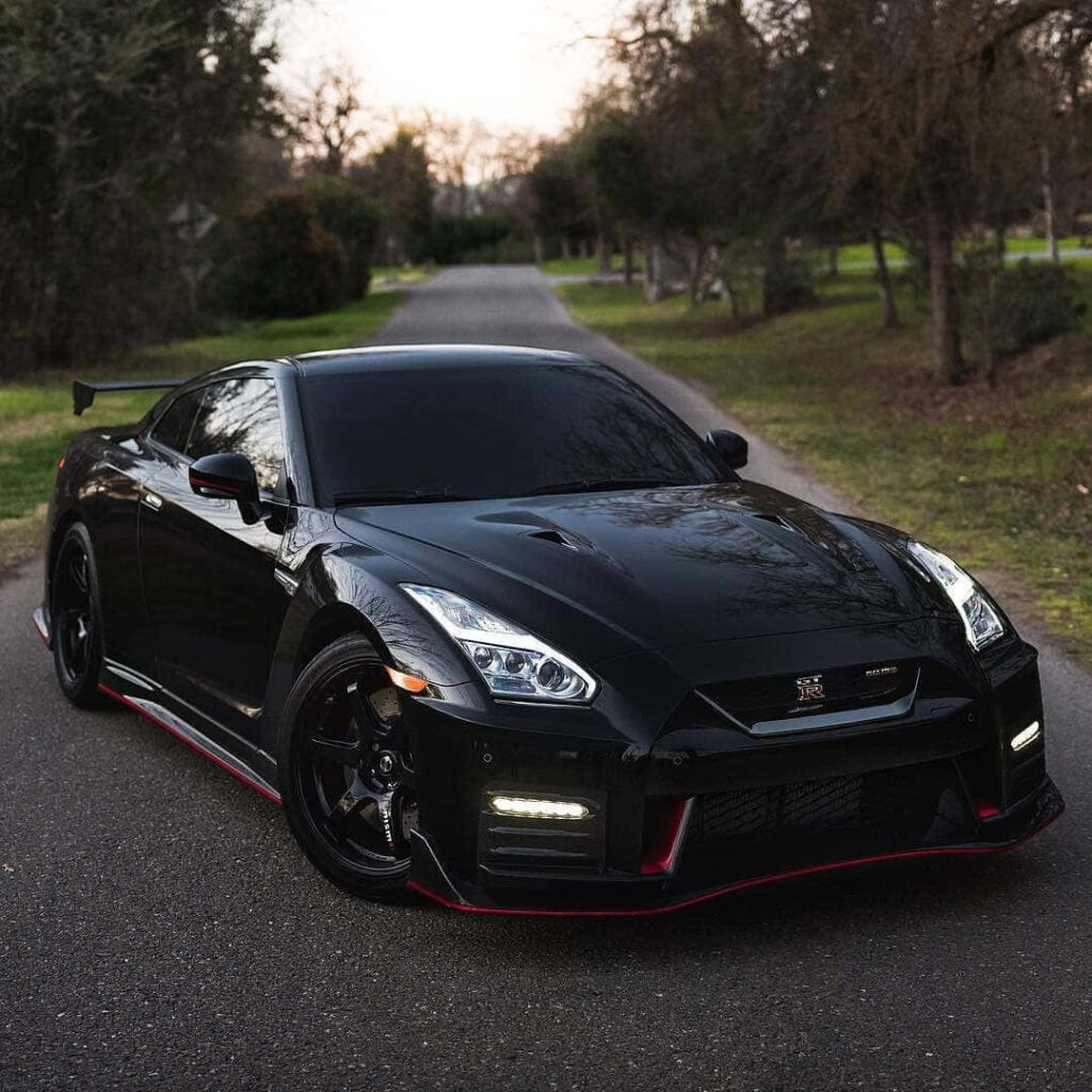 Black Nissan R35 GTR parked on tree-lined road showcasing aggressive sleek aerodynamic design wallpaper
