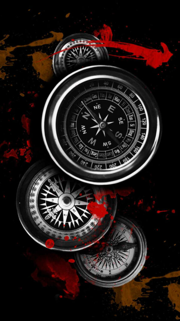 Black and silver compasses layered diagonally on black background with red brown paint splatters wallpaper