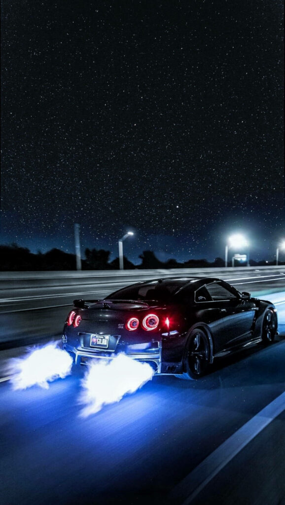 Black sports car racing at night with bright blue exhaust flames under starry sky wallpaper