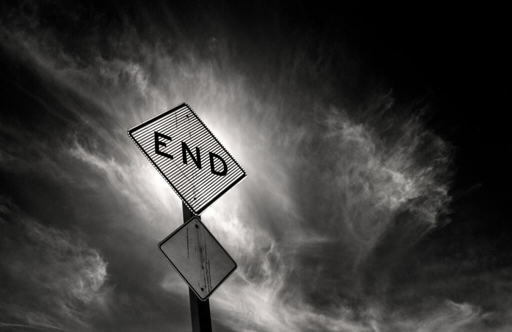 Dramatic Black and White Wallpaper: Swirling Clouds & Weathered END Sign