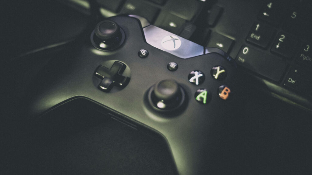Contrasting Consoles: A Striking Snapshot of Xbox One Gamepad and Keyboard in Shadow Wallpaper