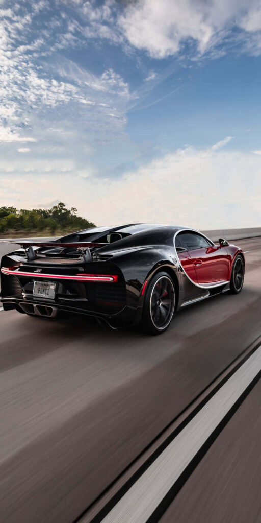 Black and red Bugatti Chiron speeding on highway vibrant sky sleek powerful rear view wallpaper
