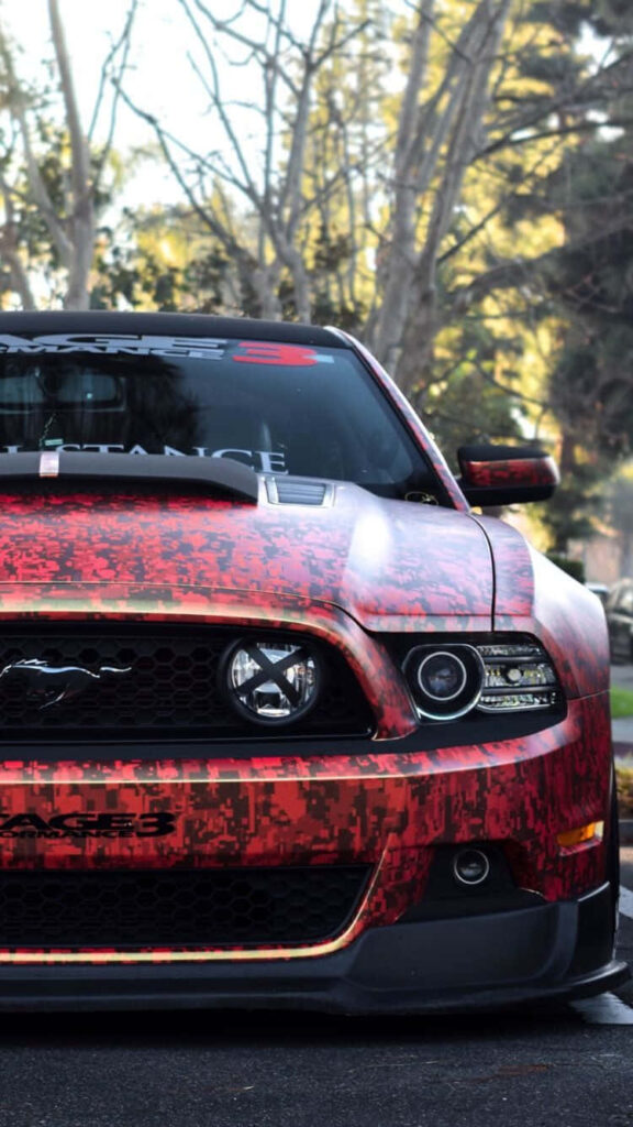 Black and red Mustang with digital camo design parked outdoors perfect for iPhone wallpaper background