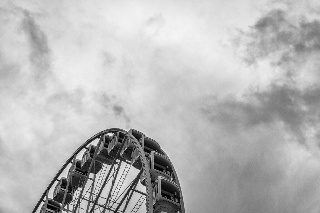Dramatic Black and White Ferris Wheel Wallpaper Against Cloudy Sky