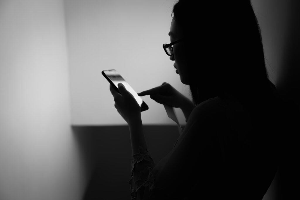 Girl on Phone: Dramatic Black and White Silhouette in Dim Light Wallpaper
