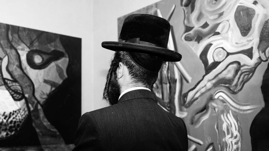 Black and white photo Hasidic Jewish man in traditional hat viewing abstract modern art in gallery Wallpaper