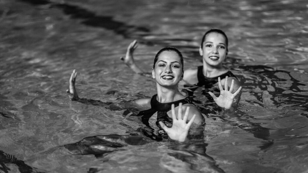 Black and white wallpaper of two synchronized swimmers performing a graceful choreographed routine