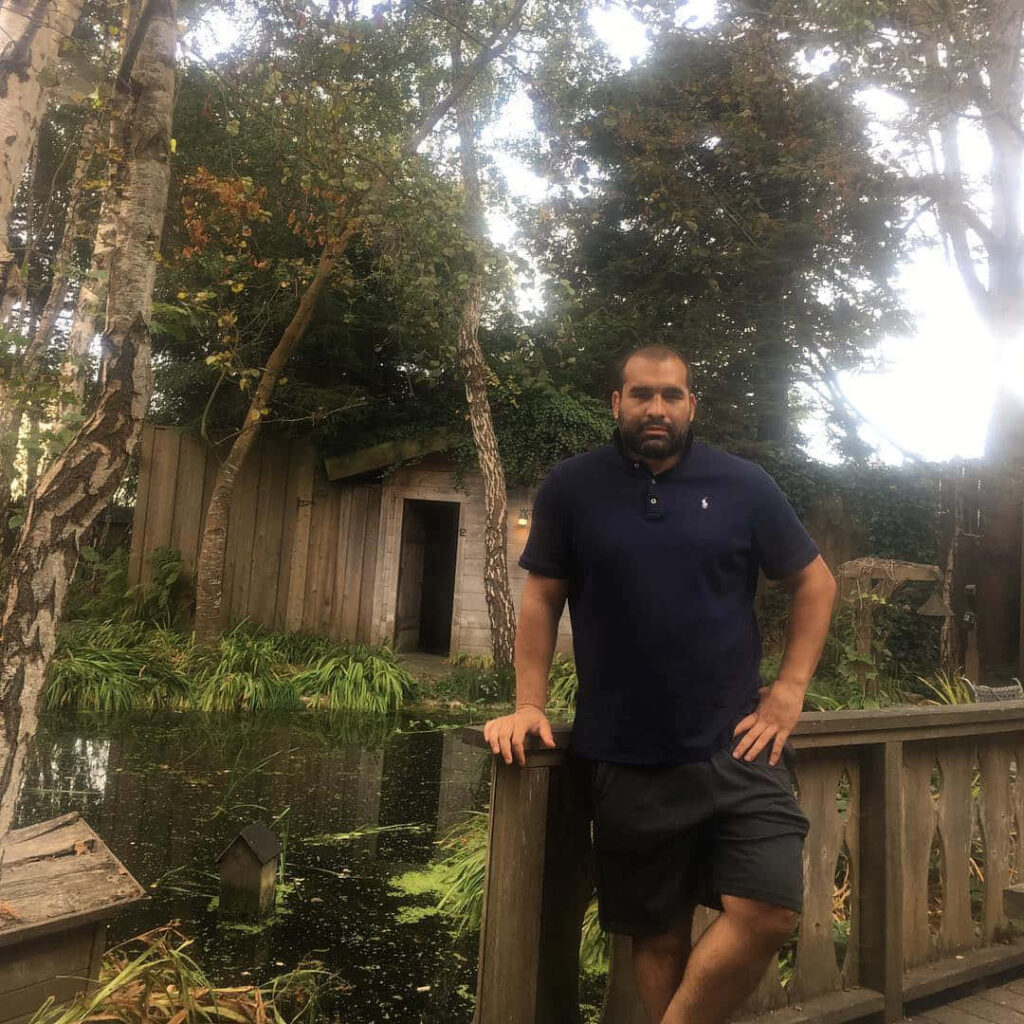 Blagoy Ivanov by rustic wooden railing near calm river with lush green natural scenery wallpaper