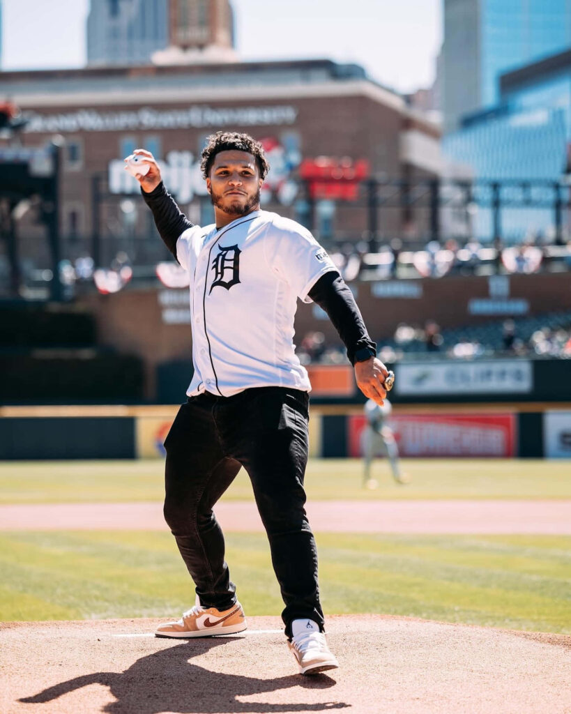 Blake Corum pitching ceremonial first pitch at baseball game with city skyline background Wallpaper