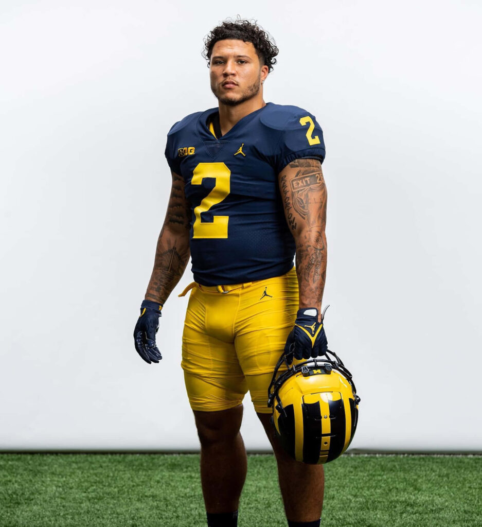 Blake Corum Michigan football player number 2 holding helmet confident pose wallpaper background