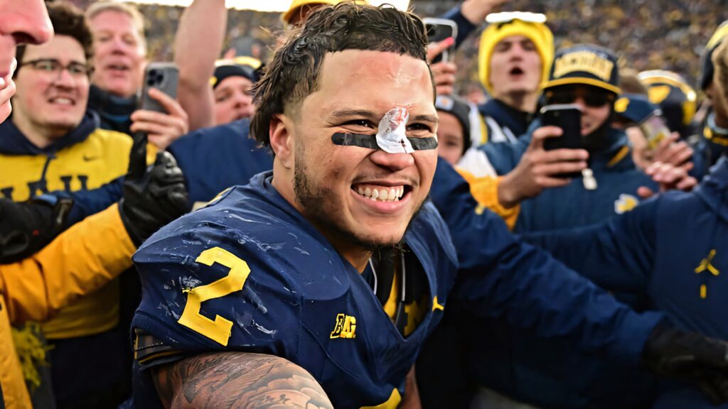 Blake Corum celebrating victory with fans on field vibrant dynamic football wallpaper background