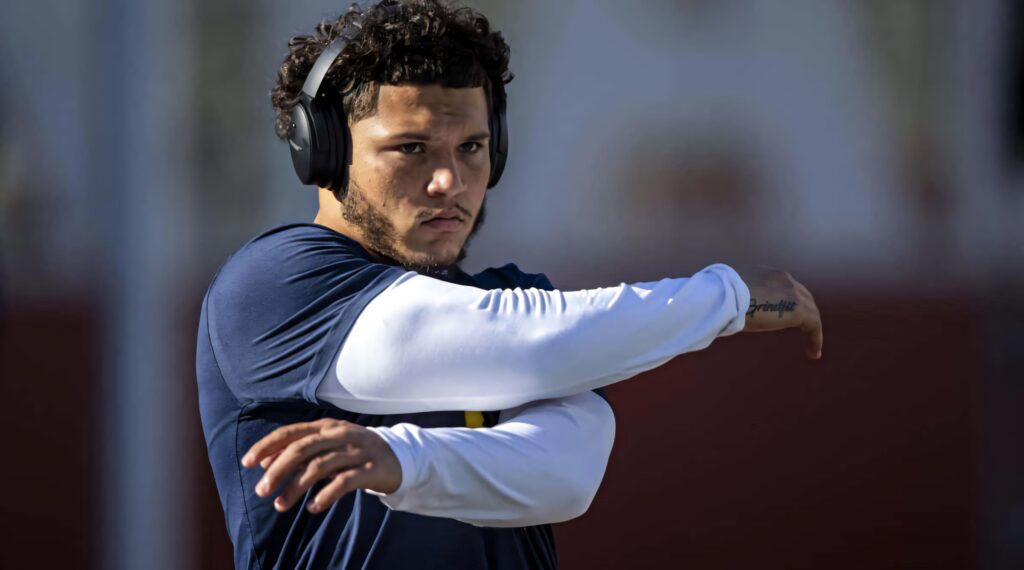 Athlete Blake Corum stretching and warming up focused with headphones ready for training wallpaper