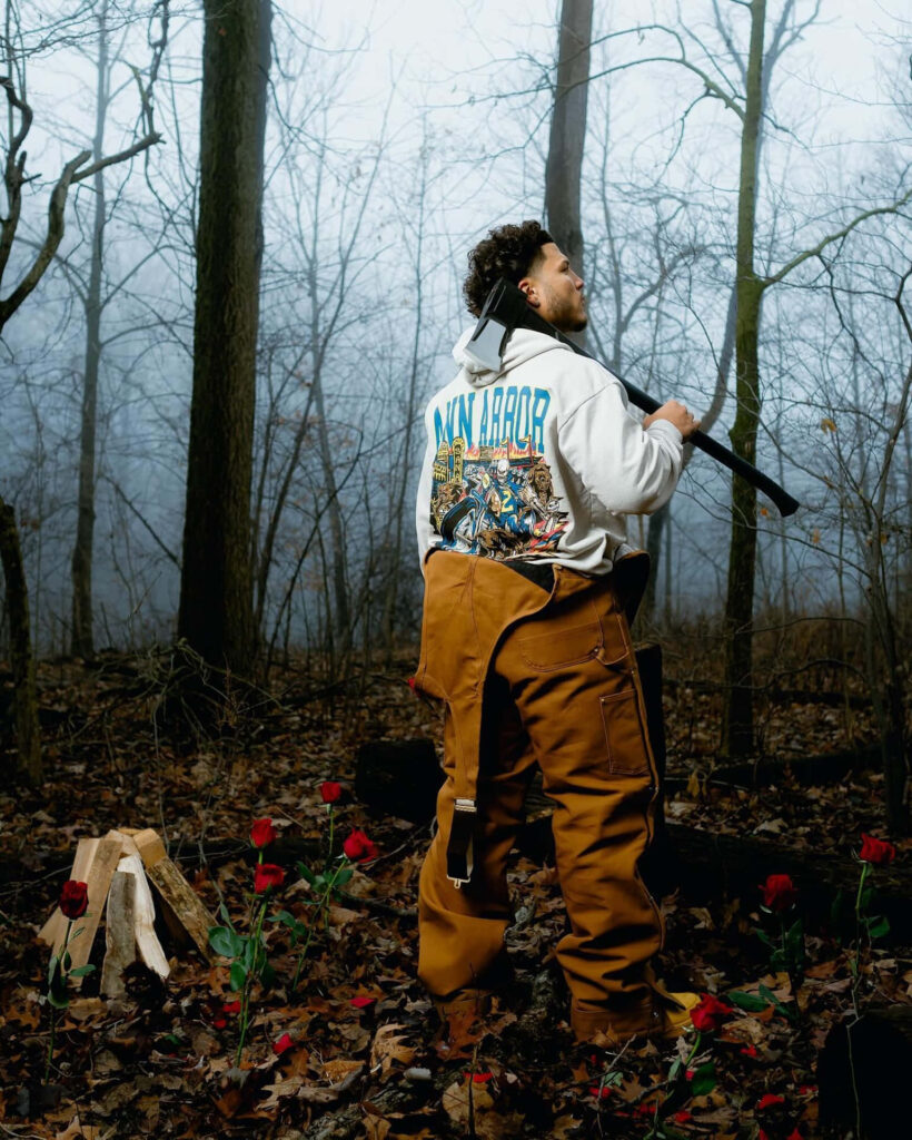 Blake Corum in misty forest holding axe surrounded by red roses and fallen leaves wallpaper