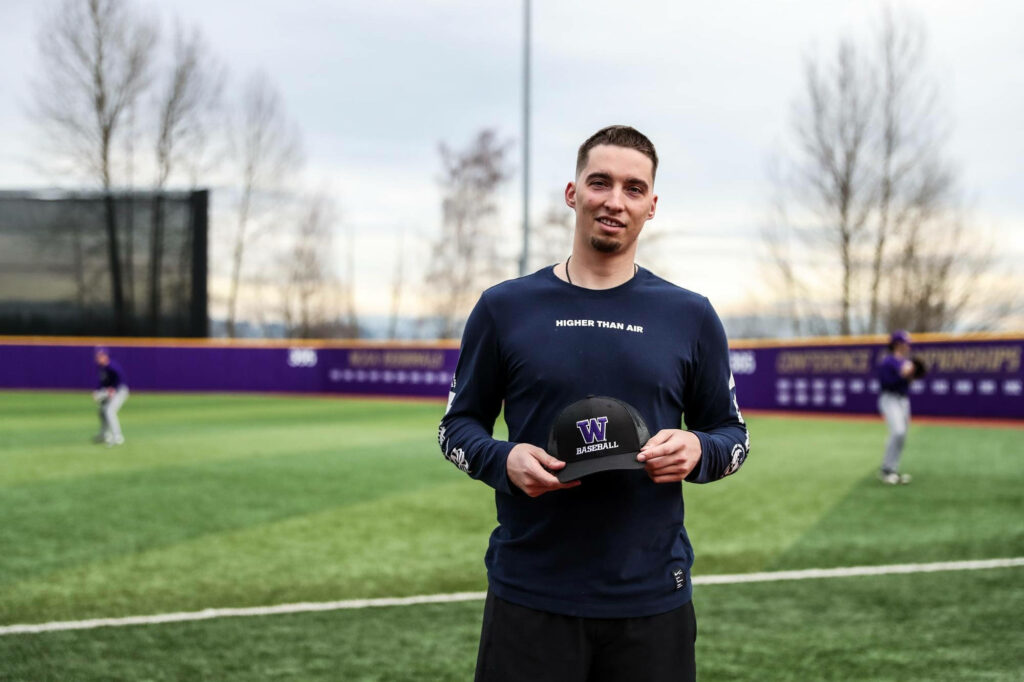 Blake Snell smiling on baseball field holding cap with players practicing under cloudy sky wallpaper