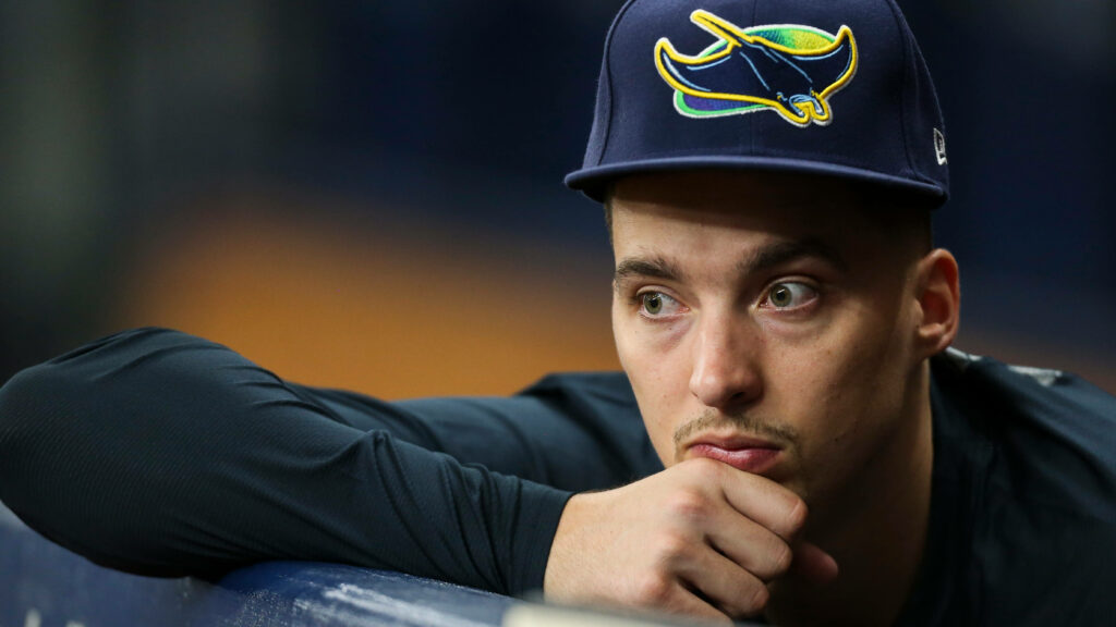 Blake Snell closeup in team cap thoughtfully watching baseball game from dugout wallpaper background