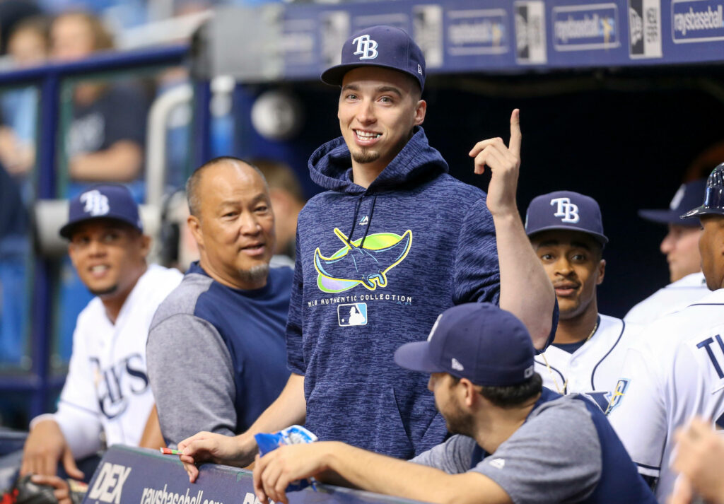 Blake Snell in Tampa Bay Rays hoodie smiling and pointing up in dugout with teammates watching Wallpaper