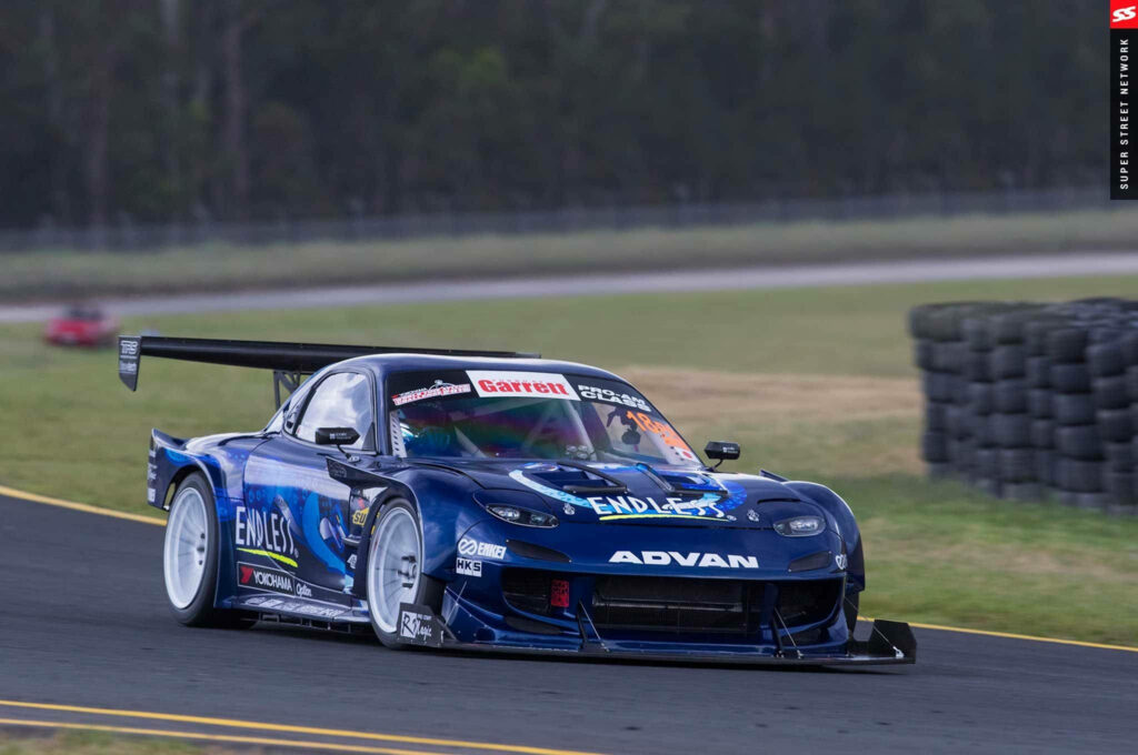 Speeding Through the Curve: An Adorned Blue Mazda Rx-7 Ignites the Race Track Wallpaper